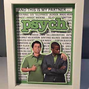 May include: Framed artwork featuring two men from the TV show "Psych." The word "psych" is in large green letters. The artwork includes a list of names and phrases. The frame is white.