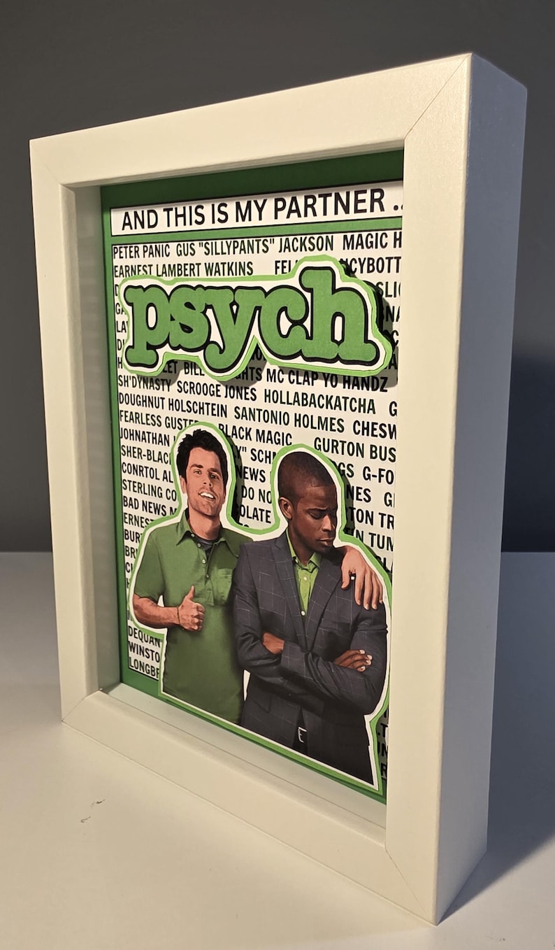 May include: Framed artwork featuring the word "Psych" in green, with two men in the center. The background includes text and the phrase "AND THIS IS MY PARTNER." The frame is white.
