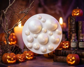 May include: A circular white silicone mould featuring various sizes of hemispherical cavities. The mould has a smooth, matte finish and is designed for creating multiple round shapes simultaneously in a single casting process.