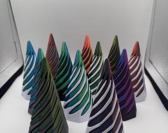 May include: A group of cone-shaped ornaments with a white base and striped tops in various colours, including blue, green, orange, and purple. The objects have a geometric design and are arranged on a white surface. The height of the objects is approximately 10 cm.