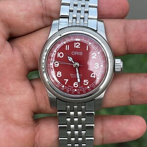 Reloj automático mecánico Oris con corona grande, puntero y fecha, esfera roja.