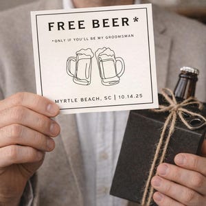 May include: A square card with the text "FREE BEER * ONLY IF YOU'LL BE MY GROOMSMAN" and two beer mugs. Below is "MYRTLE BEACH, SC | 10.14.25". A brown bottle is in a black box tied with twine.