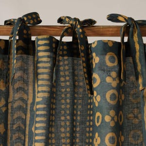 Peut inclure: Rideaux à motifs bleu canard et or avec attaches. Le tissu présente un motif répété de points, de lignes et de formes florales dorées sur un fond bleu canard. Les attaches sont faites du même tissu.