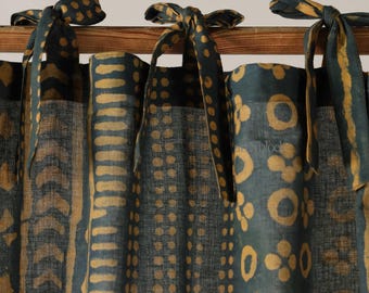 May include: Dark teal and gold patterned curtains with tie closures. The fabric features a repeating pattern of dots, lines, and floral shapes in gold against a dark teal background. The tie closures are made of the same fabric.