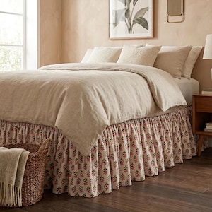 Può includere: Un letto con copripiumino in lino beige tinta unita e cuscini abbinati, completato da una balza per letto arricciata che presenta un motivo ripetuto di piccoli fiori rosa e foglie verdi su uno sfondo color crema.