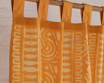 May include: Mustard yellow curtains with a repeating white pattern. The curtains are hanging from a wooden rod with matching yellow fabric loops. The pattern includes curved and linear shapes.