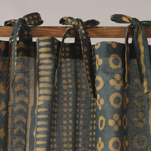 May include: Dark teal and gold patterned curtains with tie closures. The curtains feature a repeating pattern of gold shapes on a dark teal background. The tie closures are made of the same fabric and are tied in bows.