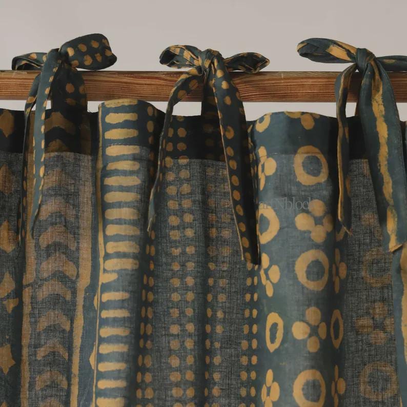 May include: Dark teal and gold patterned curtains with tie closures. The curtains feature a repeating pattern of gold shapes on a dark teal background. The tie closures are made of the same fabric and are tied in bows.