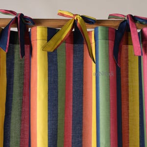 May include: Vibrant striped curtains with matching fabric ties. The curtains display vertical stripes in red, orange, yellow, green, and blue. The ties are in complementary colours, enhancing the window dressing's aesthetic appeal.
