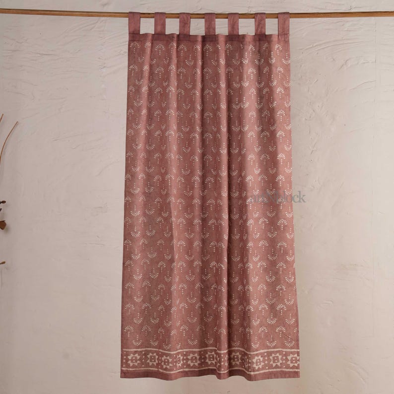 May include: A dusty rose curtain with a repeating white pattern of stylized arrows. The curtain has a decorative border at the bottom and is hung from a wooden rod with fabric loops. The fabric has a textured appearance.