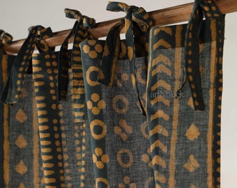 May include: Dark teal and mustard yellow patterned curtains. The fabric features repeating geometric and floral designs. The curtains are tied to a wooden rod with matching teal fabric ties. The text "artNblock" is visible on the fabric.