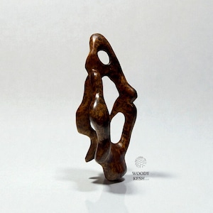 May include: A brown, abstract wooden sculpture with organic shapes and open spaces. The sculpture has a smooth, polished finish and stands upright against a white background. The sculpture is a decorative art piece.
