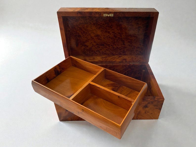 May include: Open wooden jewelry box with a lift-out tray. The box is made of a dark, patterned wood, with a lighter wood interior. The tray is divided into four compartments. The box is open, revealing the interior.