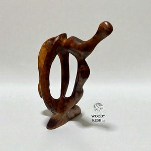 May include: A handcrafted wooden sculpture with a unique, abstract design. The sculpture is made of a rich, dark brown wood and features flowing lines and organic shapes. The base is flat, and the sculpture stands approximately 6 inches tall.