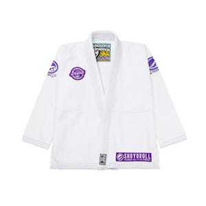 May include: White Jiu-Jitsu gi with purple and yellow accents. Features the "Shoyoroll" logo on the chest, sleeve, and pants. The gi has a V-neck design and is made of a durable material. The gi is designed for martial arts training and competition.