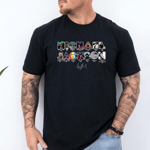 May include: A black short-sleeved t-shirt featuring the text MICHAEL JACKSON in large block letters. Each letter contains a small photographic image of the artist from different eras, with the artist's signature printed in white below the text.