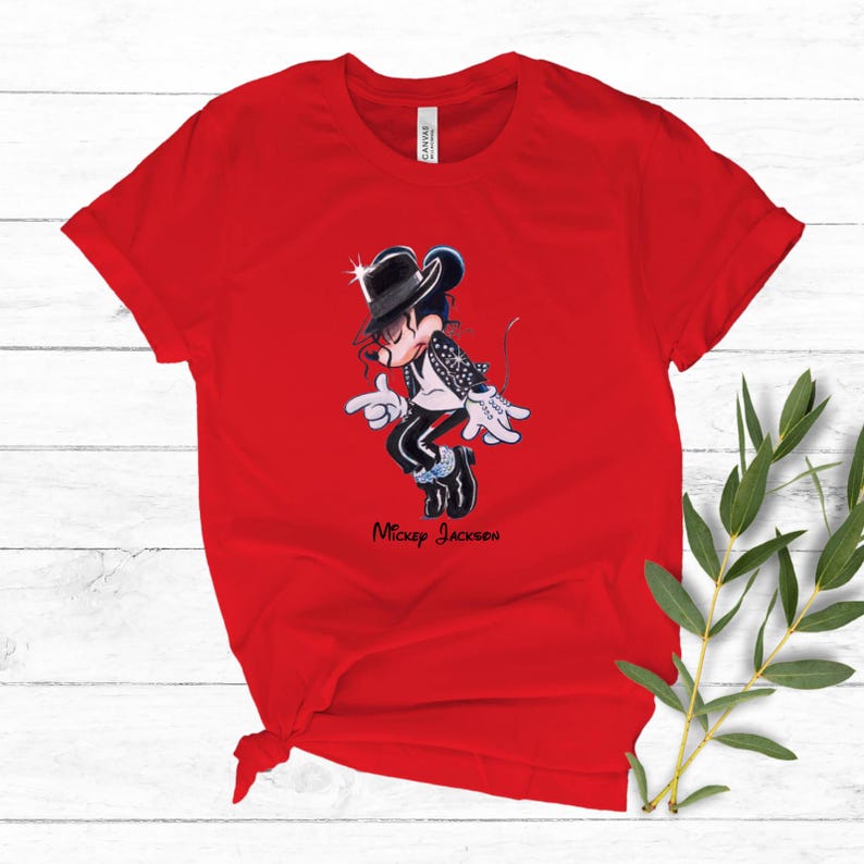 May include: A bright red short-sleeved t-shirt featuring a graphic of a cartoon mouse dressed in a black fedora, white shirt, and black jacket with white accents. The character is in a dancing pose with the text "Mickey Jackson" printed below.