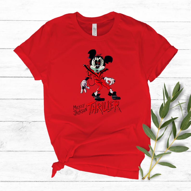May include: A bright red short-sleeved t-shirt featuring a graphic of a cartoon mouse dressed in a red jacket and black trousers. The graphic includes the text "MICKEY JACKSON" and "THRILLER" in a stylised black and red font below the character.