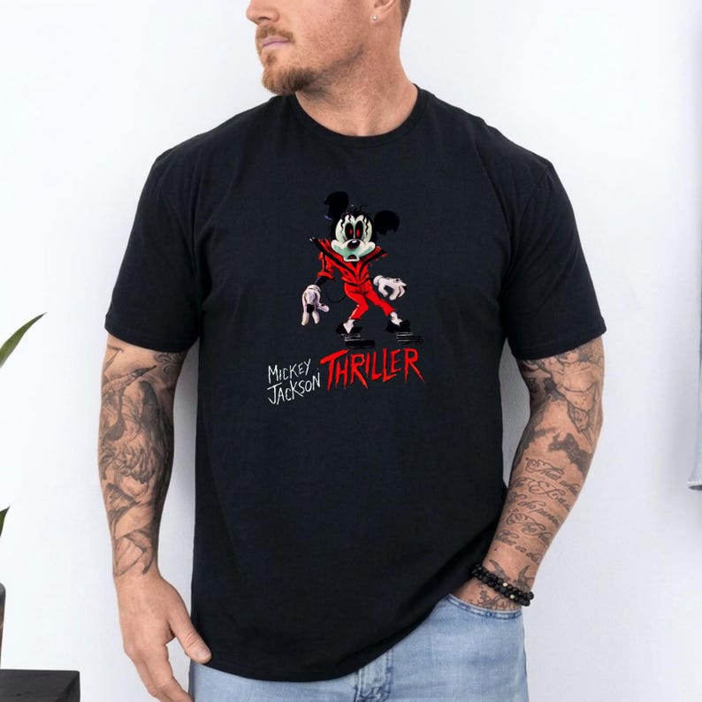 May include: A black short-sleeve t-shirt featuring a graphic of a cartoon mouse dressed in a red jacket. The mouse has a stylised face with dark eyes and is posed in a dance stance. Below the graphic, the text reads Mickey Jackson THRILLER.