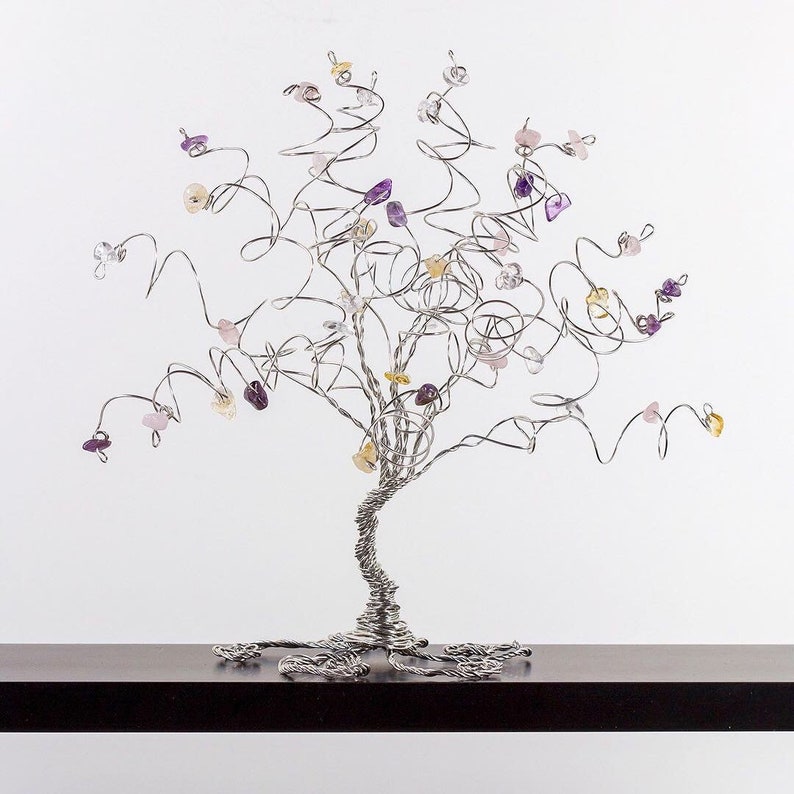 May include: A silver wire tree sculpture with purple, pink, and yellow gemstones attached to the branches.