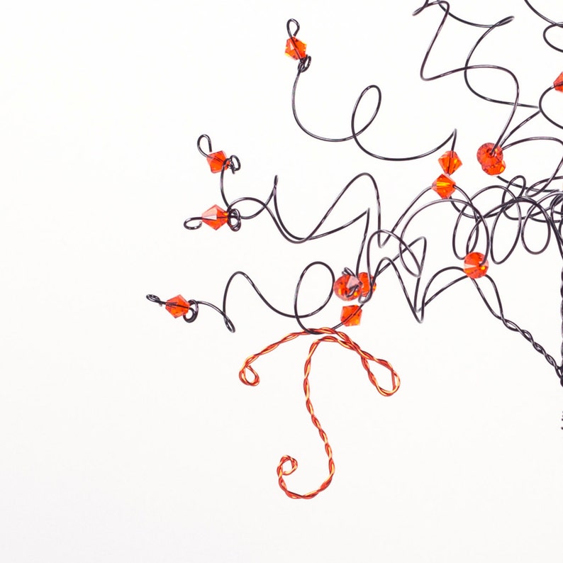 Puede incluir: Una escultura de alambre de un &aacute;rbol con cuentas de vidrio naranja. El &aacute;rbol est&aacute; hecho de alambre delgado que se tuerce y gira para crear ramas. Las cuentas est&aacute;n unidas a las ramas y est&aacute;n dispuestas en un patr&oacute;n aleatorio.