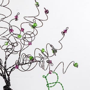 Puede incluir: Una escultura de alambre de un &aacute;rbol con cuentas verdes y moradas. El &aacute;rbol est&aacute; hecho de alambre retorcido y las cuentas est&aacute;n unidas a las ramas.