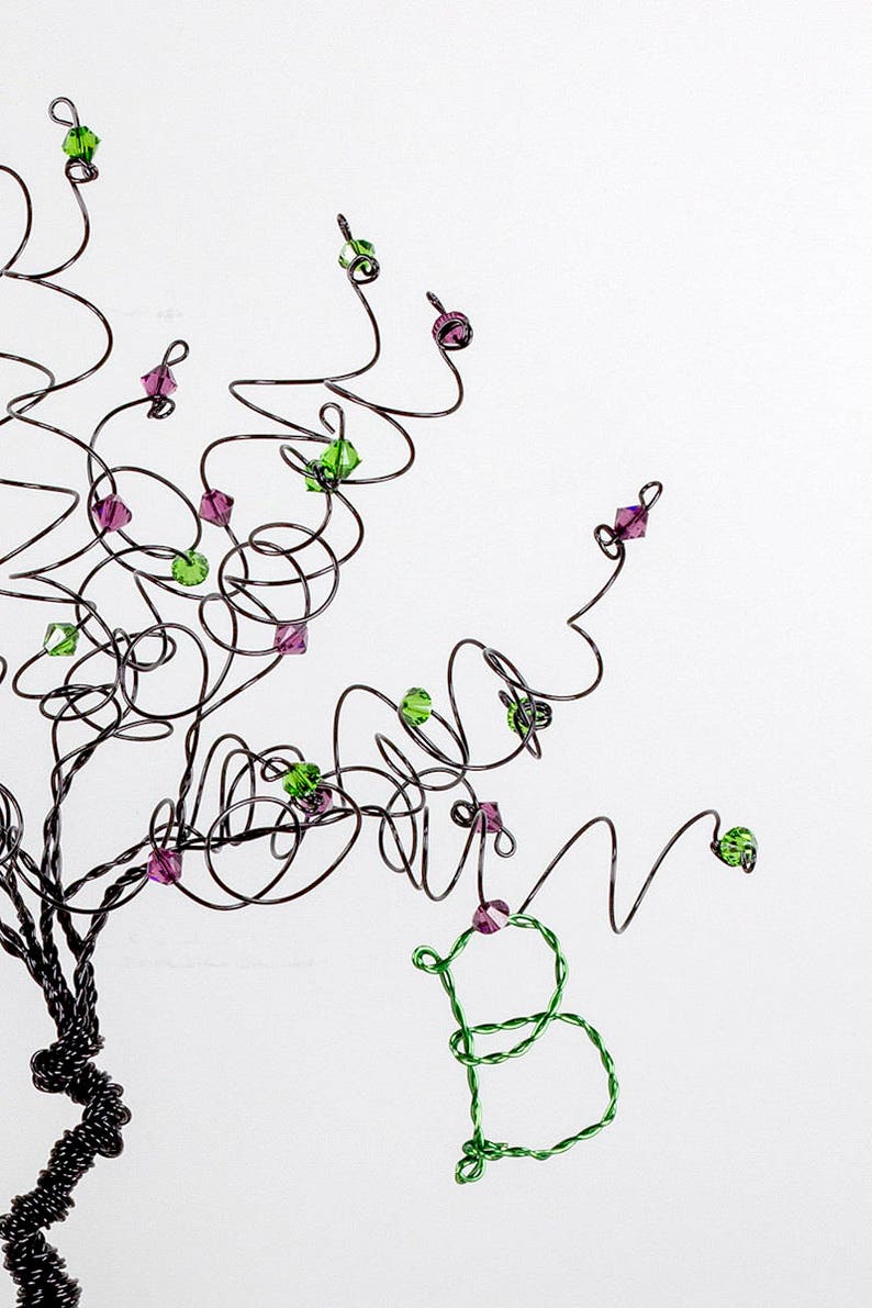 Puede incluir: Una escultura de alambre de un &aacute;rbol con cuentas verdes y moradas. El &aacute;rbol est&aacute; hecho de alambre retorcido y las cuentas est&aacute;n unidas a las ramas.