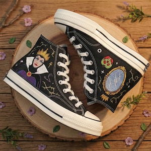 May include: A white ceramic mug with a black handle and the text "But First, Coffee" in a black, handwritten-style font. The mug is on a white surface.