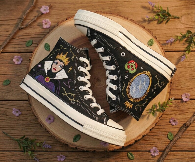 May include: A white ceramic mug with a black handle and the text "But First, Coffee" in a black, handwritten-style font. The mug is on a white surface.