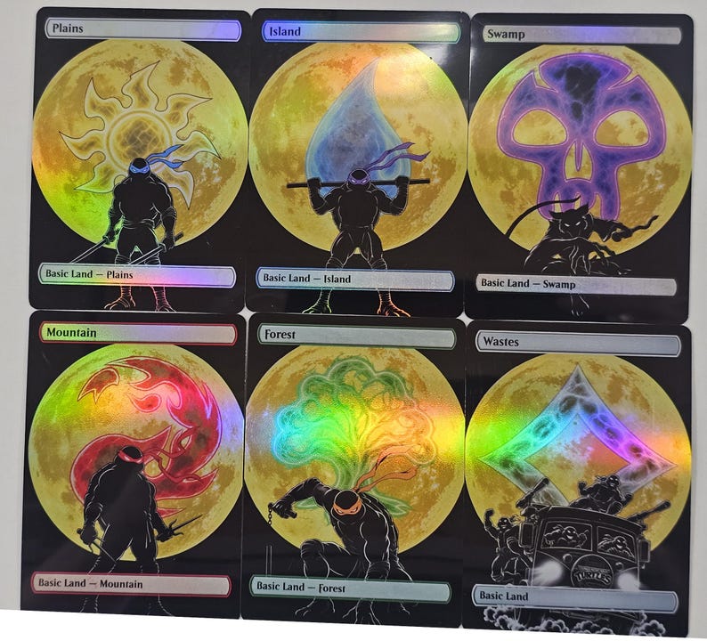 Op de afbeelding: Zes holografische ruilkaarten met silhouetten van Teenage Mutant Ninja Turtles tegen een grote gele maan. Elke kaart toont een ander landtype: Plains, Island, Swamp, Mountain, Forest en Wastes, met bijbehorende elementaire symbolen en personagehoudingen.