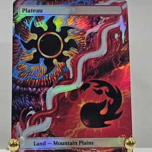May include: A rectangular trading card with a holographic finish featuring the text Plateau at the top and Land - Mountain Plains at the bottom. The artwork displays a black sun symbol and a black flame shape against a vibrant red and purple background.