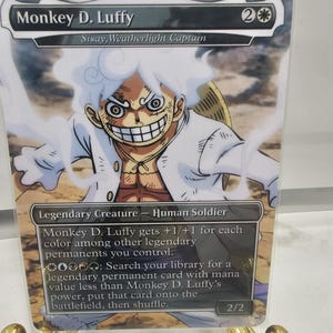 May include: A collectible card featuring Monkey D. Luffy from the anime series. The card displays a vibrant illustration of the character with white hair and a wide grin. Text includes "Monkey D. Luffy" and "Legendary Creature - Human Soldier".