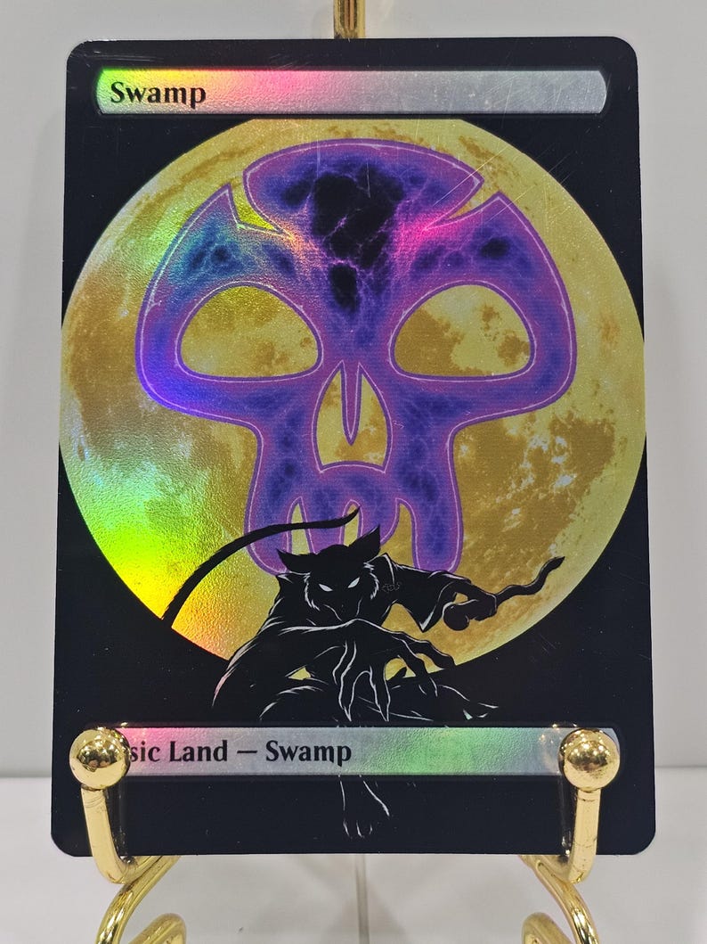Op de afbeelding: Een rechthoekige ruilkaart met een zwarte rand en een holografische afwerking. De tekst bovenaan luidt Swamp en de tekst onderaan luidt Basic Land - Swamp. Een grote gele maan bevindt zich achter een paars schedelpictogram en een zwart silhouet.