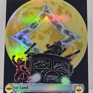 Op de afbeelding: Een holografische ruilkaart getiteld Wastes, met een grote gele maan achter een ruitvormig symbool. Daaronder staan de Teenage Mutant Ninja Turtles afgebeeld in hun busje, met &eacute;&eacute;n schildpad op het dak en twee zichtbaar door de voorruit.