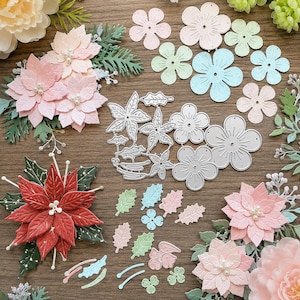 May include: A collection of metal cutting dies for crafting, featuring various flower and leaf shapes, alongside assembled paper poinsettia flowers in red and light pink, accented with small white beads and green foliage elements.