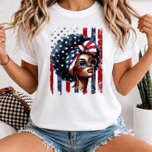 Puede incluir: Camiseta blanca con un gráfico de una mujer con afro, gafas de sol y pañuelo con diseño de estrellas y rayas. El fondo incluye rayas y estrellas rojas y azules, que se asemejan a la bandera estadounidense.