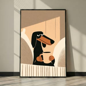Peut inclure: Une impression d'art encadrée représentant une illustration stylisée d'un chien teckel noir et marron assis dans un lit. Le chien a une expression grincheuse et tient une tasse de couleur claire avec ses deux pattes. Le fond utilise des tons beiges.