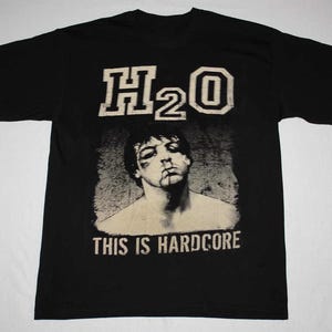 Puede incluir: Una taza de cerámica blanca con un asa negra y el texto "But First, Coffee" en negro, con una fuente de estilo manuscrito. La taza está sobre una superficie blanca.