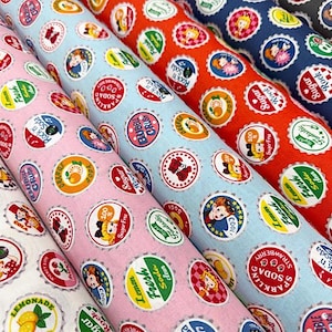 May include: Close-up of several rolls of fabric with a repeating pattern of vintage soda bottle caps. The caps feature cartoon characters and text like "Rock n Soda" and "Sugar Free" in various colors including pink, blue, red, and white.
