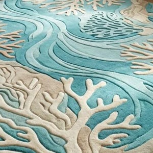 Hand-tufted 100% wool area rug featuring a 3D textured coral reef design in shades of teal, blue, and ivory, styled in a modern coastal living room and nursery.