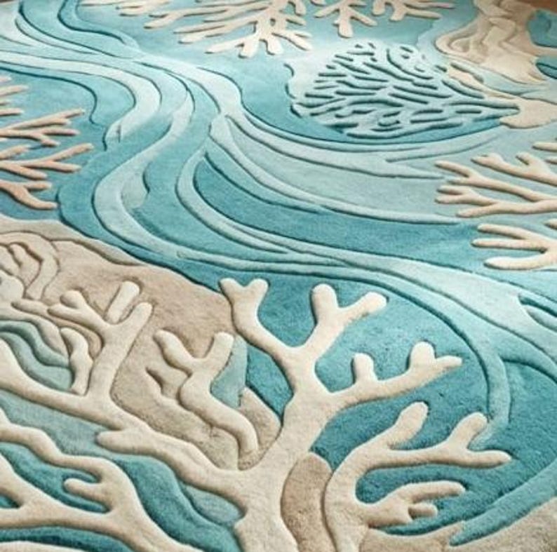 Hand-tufted 100% wool area rug featuring a 3D textured coral reef design in shades of teal, blue, and ivory, styled in a modern coastal living room and nursery.