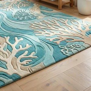 Hand-tufted 100% wool area rug featuring a 3D textured coral reef design in shades of teal, blue, and ivory, styled in a modern coastal living room and nursery.