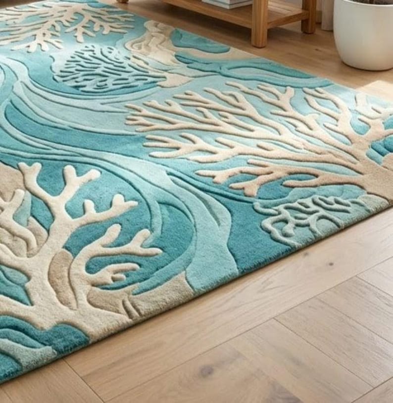 Hand-tufted 100% wool area rug featuring a 3D textured coral reef design in shades of teal, blue, and ivory, styled in a modern coastal living room and nursery.