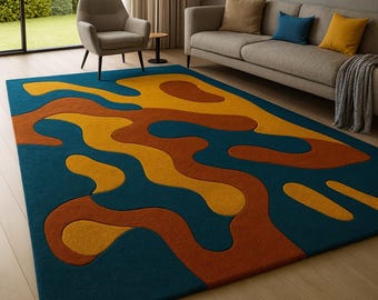 May include: A large, rectangular area rug with an abstract design. The rug features a teal blue background with flowing, organic shapes in shades of gold and rust. The rug is placed on a light-colored wooden floor, and is in a living room setting.
