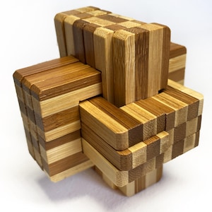 May include: A wooden puzzle with a complex, interlocking design. The puzzle is constructed from rectangular blocks of light and dark brown wood, creating a visually interesting pattern. The blocks are arranged in a three-dimensional structure.