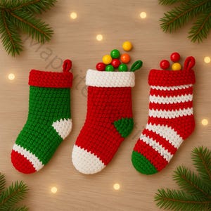 Puede incluir: Tres calcetines de Navidad hechos a mano en ganchillo verde, rojo y blanco. Un calcetín es verde con detalles blancos, otro es rojo con detalles blancos y el tercero es de rayas rojas y blancas. Cada calcetín está lleno de caramelos de colores.