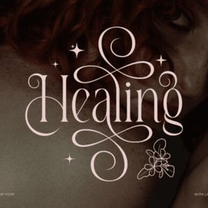 May include: Elegant serif font design with the word "Healing" in a flowing script. The image features a soft, neutral color palette with decorative elements like stars and a floral illustration. Text at the bottom reads "A New Elegant Serif Font" and "With Ligature Variations."