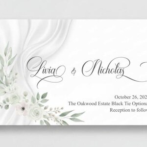 May include: A white wedding invitation with elegant script lettering reading "Livia & Nicholas." The card features floral accents in soft green and white, with the date "October 26, 2024" and event details.