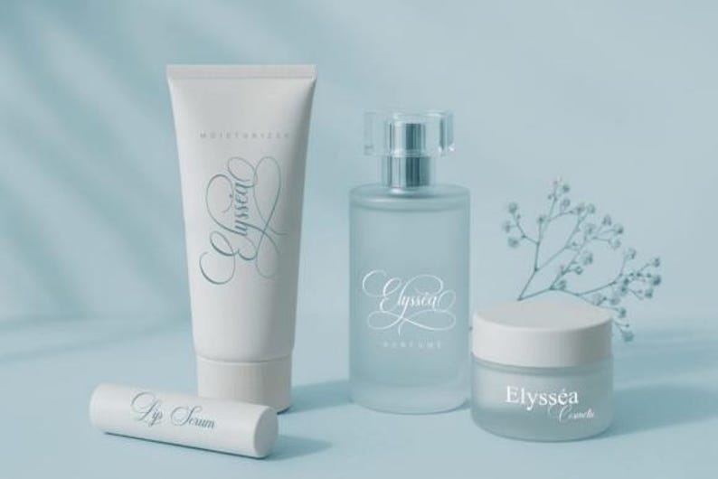 May include: Cosmetic product set featuring a white tube of moisturizer, a perfume bottle, a jar of cream, and a lip serum tube. All items have the word "Elyss&eacute;a" in a script font. The products are arranged on a light blue surface.