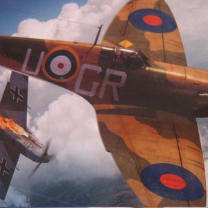 May include: A brown and green camouflage airplane with a red, white, and blue roundel on the wing, flying over clouds. The airplane is labeled "UOGR". A smaller, gray airplane with black markings is on fire and falling from the sky.